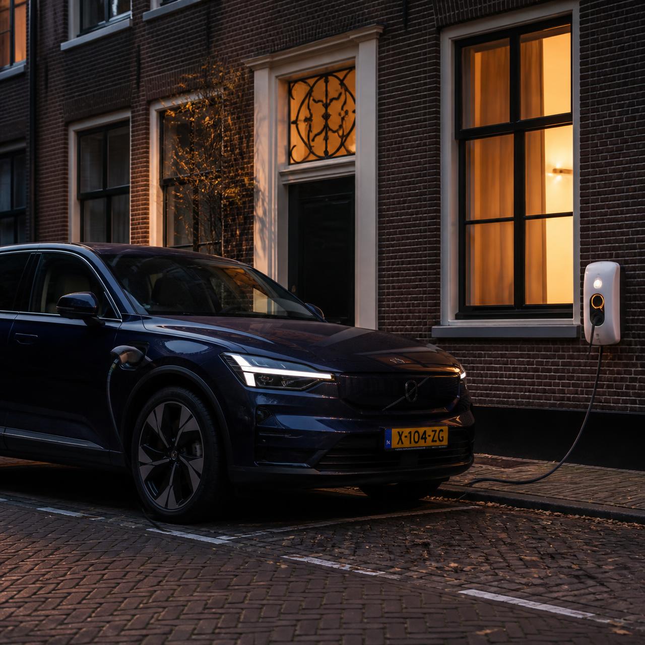 Dark blue electric SUV charging at dusk on a white wall charger against a Dutch brick facade